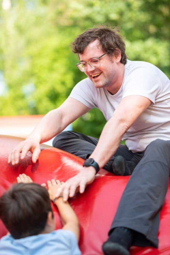 Ein Vater spielt mit seinem Sohn auf einem roten Spielgerät