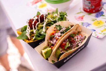 Two tacos and a falafel bowl in a black cardboard box printed with ‘chidonkey’. The tacos are filled with diced avocado, pieces of red pepper, chopped red onion and coriander; the bowl contains falafel balls, rocket, mango, sweetcorn and a white sauce with black sesame seeds.